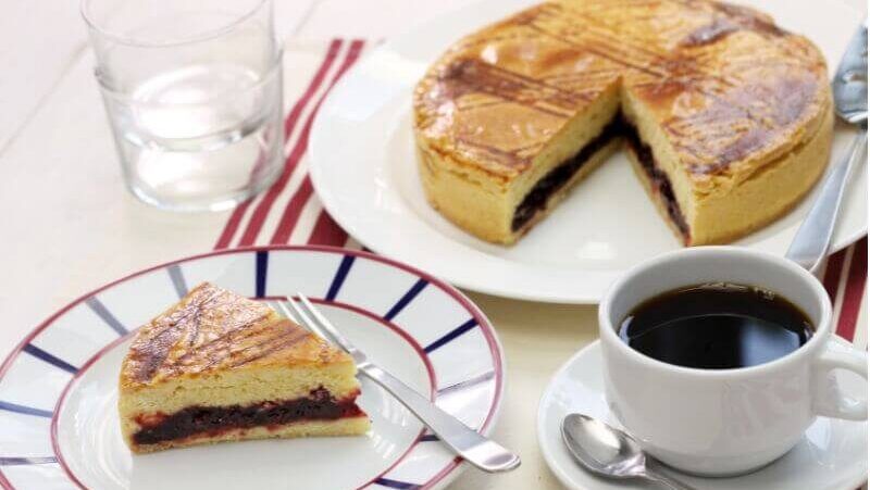 ガトーバスクの一切れとホール、コーヒーがテーブルに並ぶ