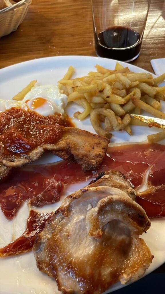フライドポテト、ベーコン、肉、目玉焼きが乗ったプレートのアップ