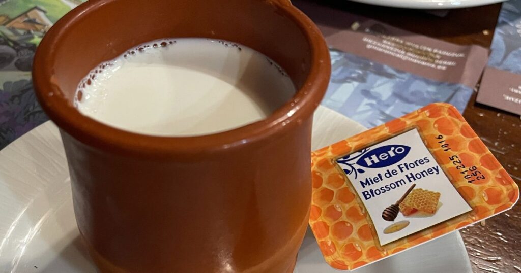 茶色い伝統的陶器に入ったクアハーダ。横に蜂蜜が添えられている