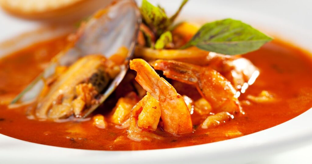 貝やエビを添えた赤色の魚介のスープ
